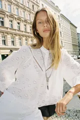 Camisa blanca de manga larga con cuello con volantes y bordados perforados. Cierre frontal con botones a tono.