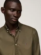 Camisa verde militar de corte regular, con cuello abotonado y mangas largas con puños abotonados. Logo de Tommy Hilfiger bordado en el pecho.