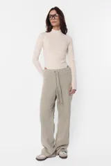 Pantalón de jogging color beige, de frisa y corte relajado. Con cintura de rib al tono, cordones con punteras metálicas y ojalillos personalizados de marca. Detalle de bordado a contratono en ambos laterales de pierna.