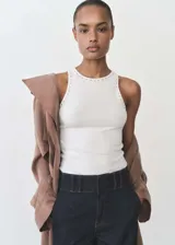 Musculosa blanca de algodón con cuello redondo y detalle de tachuelas plateadas en el cuello y las sisas. Diseño ajustado al cuerpo.