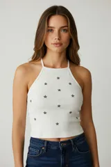 Musculosa blanca con estampado de estrellas grises, breteles finos y cuello halter.