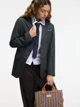 Blazer gris oscuro de lana con cuello solapa y cierre con botones. Presenta pedrería decorativa en la parte delantera y trasera.