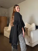 Ruana negra tejida a mano con lana merino, punto arroz y flecos.