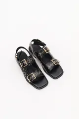 Sandalias bajas color crema con apliques de tachas metálicas y hebillas plateadas.