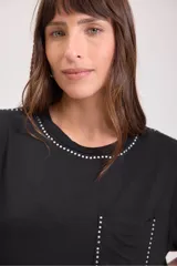 Remera negra de corte recto con cuello redondo y bolsillo en el pecho. Detalles de tachas plateadas en cuello, mangas y bolsillo.