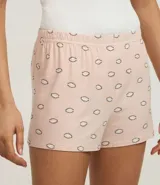 Conjunto de pijama short doll compuesto por un top blanco de rib con breteles finos y detalle de encaje en el escote, y un short rosa con estampado de ojitos y cintura elástica.