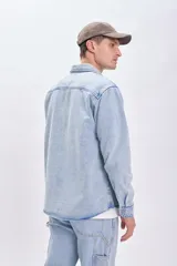 Sobrecamisa de jean celeste con dos bolsillos frontales con solapa y cierre abotonado.