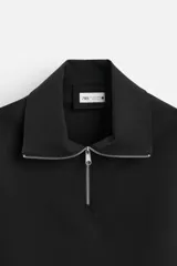 Sudadera negra de corte relaxed fit, con cuello alto y cierre frontal de cremallera metálica.