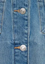 Chaqueta de jean celeste de corte oversize, con cuello camisero, cierre frontal con botones metálicos, dos bolsillos de parche con botón en el pecho y dos bolsillos laterales.