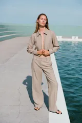 Pantalón de tiro bajo color beige, con bolsillos delanteros y falsos bolsillos de vivo en la espalda. Piernas rectas y cierre frontal con cremallera, botón interior y ganchos.