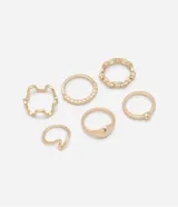 Set de seis anillos dorados de metal con diferentes diseños: uno con detalle de lunar, dos ondulados, uno de cadena, uno con lunar y uno irregular.