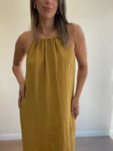 Vestido largo de lino color crudo, con escote halter fruncido y abertura lateral en la falda.