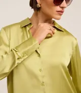 Camisa blanca de satén con cuello inglés, manga larga y cierre frontal con botones.