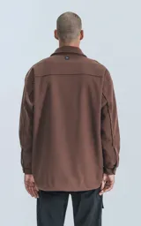 Chaqueta marrón de paño con cuello clásico, cierre frontal con botones, dos bolsillos de parche en el pecho y corte holgado.