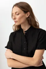 Camisa negra de lino con cuello mao y volados en cuello y mangas cortas.