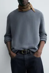Sweater azul de punto con textura, corte holgado, cuello redondo y mangas largas con puños acanalados.