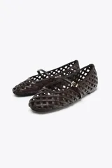 Zapato plano tipo bailarina color marrón oscuro, con capellada trenzada y tira delantera con hebilla metálica. Suela plana de 1 cm de altura y punta redonda.