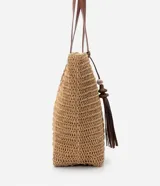 Bolso de playa negro tejido en paja de papel, con asas de hombro en cuero sintético y detalle de borla colgante.