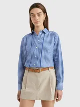 Camisa de manga larga a rayas verticales azules y blancas, con cuello inglés y corte amplio. Presenta detalles distintivos de la marca Tommy Hilfiger y logo bordado en el puño.