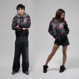 Campera con cierre frontal, capucha forrada con pelo sintético gris y estampado de texto y salpicaduras rojas sobre fondo negro.