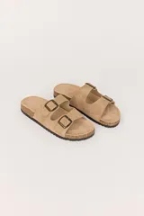 Sandalias planas color beige con dos tiras anchas sobre el empeine, cada una con hebillas metálicas ajustables.