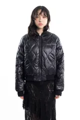 Campera bomber negra de tela satinada con cierre frontal, cuello redondo y puños y cintura elastizados. Tiene un pequeño logo bordado en el pecho y un bolsillo con cierre en la manga. Es reversible.
