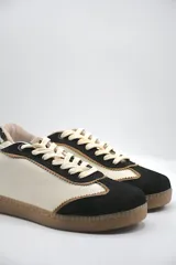 Zapatillas urbanas de cuero color beige con puntera y cordones marrones. Presentan un panel de animal print en el talón y suela de goma color caramelo.