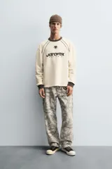Sudadera color crema de corte relaxed fit, con cuello redondo y manga larga. Presenta un estampado en el frente con la palabra "ULTRAVEX" en letras negras y la palabra "FUTURIO" debajo.