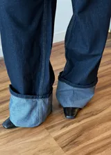Pantalón de jean azul oscuro de corte ancho con dobladillo en color gris claro.