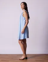 Vestido blanco de algodón y rayón, marca Dash. Cuello a la base, sin mangas y abertura central con botones. Delantera con detalle plisado y laterales con bolsillos.
