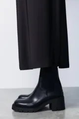 Botín Chelsea negro de cuero con caña de neopreno, tacón bloque y suela track.
