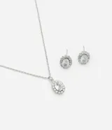Conjunto de collar y aros plateados con circonias blancas. El collar tiene una cadena fina y un colgante con una circonia ovalada rodeada de pequeñas circonias. Los aros son tipo botón con una circonia ovalada rodeada de pequeñas circonias.