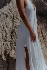Vestido largo de color blanco, con escote en V pronunciado y tiras largas que permiten anudarlo de múltiples formas. Presenta tajo en ambos laterales y forro interno.