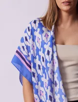 Kimono tejido color naranja con estampado geométrico en blanco y celeste, y terminación con borlas.