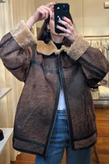 Campera gamulán marrón con cuello y puños de piel sintética color beige. Cierre frontal con cremallera y bolsillos laterales.