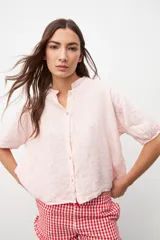 Camisa color rosa pastel, de lino, con cuello mao, manga corta y cierre frontal con botones.
