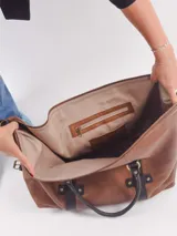 Bolso negro con detalles en cuero marrón, con doble asa de mano y cierre superior.