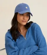 Gorra de sarga color azul con visera curva, ajuste trasero y bordado frontal de una margarita blanca con centro amarillo.