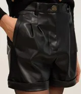 Short negro de cuero sintético, de tiro alto, con pinzas delanteras y ruedo doblado.