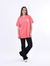 Remera color salmón con estampado frontal con la frase "The Beach Club" en letras blancas.