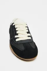 Zapatillas deportivas negras con detalle de estampado animal en la parte trasera, suela color caramelo y ajuste con cordones.