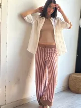 Pantalón de punto marrón con rayas verticales rosas, corte palazzo y cintura con cordón ajustable.