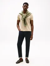 Chomba color beige con tejido jacquard, cuello tipo chomba, billetera de dos botones, logo de Tommy Hilfiger bordado en la manga y corte regular.