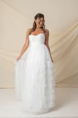 Vestido largo de fiesta color blanco, strapless, con corsé drapeado y falda amplia con volados de tul. Ideal para novias.