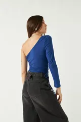 Top asimétrico blanco de una sola manga con jaretas ajustables en ambos lados del torso para regular el largo.