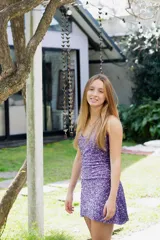 Vestido plateado con rayas horizontales negras, escote en V y breteles finos que se atan atrás del cuello. Corte en la cadera y falda con ruedo irregular y pico en lateral.