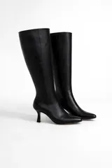 Botas altas de cuero negro, caña ajustada, punta fina y taco aguja de altura media.