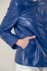 Campera azul de cuero ovino italiano, con cuello redondo, cierre frontal con broches ocultos, bolsillos laterales y detalle de capitoneado en puños y bolsillos.