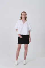 Blusa blanca de algodón con escote en V y frunces en el cuello, mangas abullonadas cortas y calce holgado.