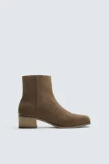 Botín de cuero negro con acabado serraje, cierre de cremallera lateral, horma cuadrada y tacón de 5 cm.